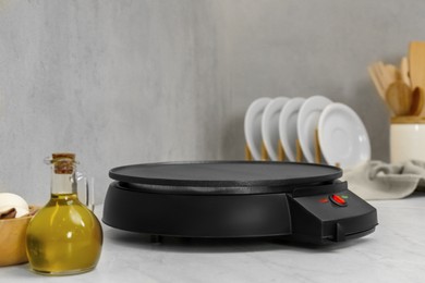 Photo of New electrical crepe maker on white marble table in kitchen