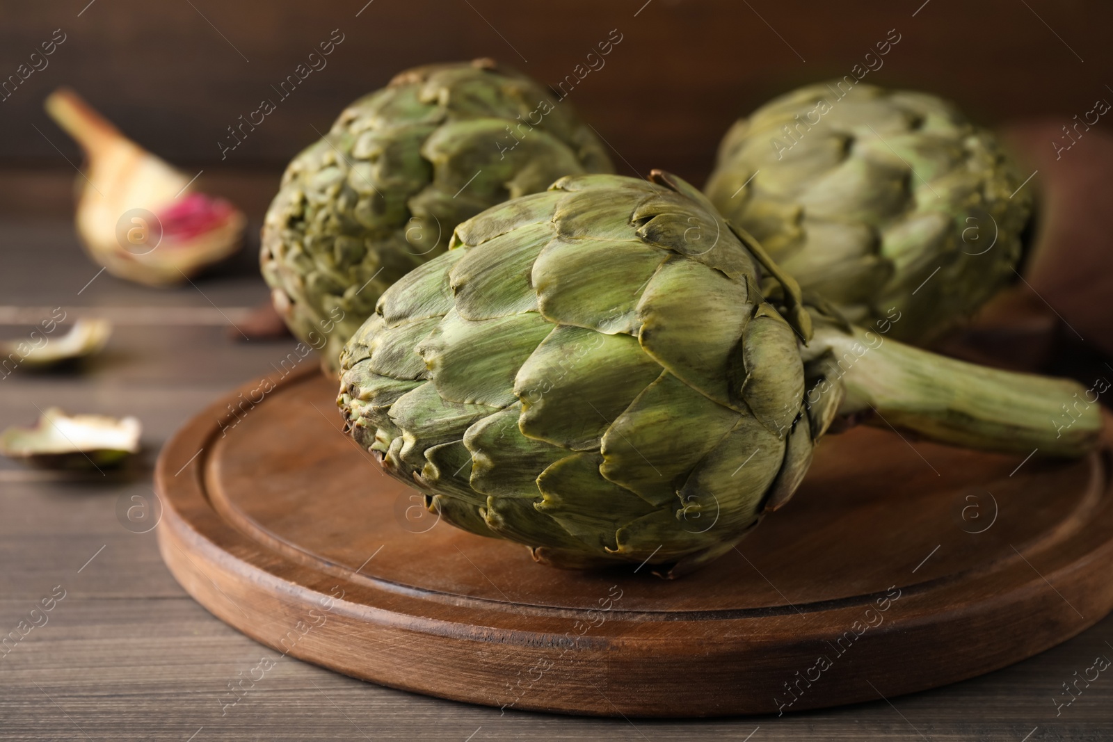 Photo of Fresh raw artichokes on wooden table, closeup