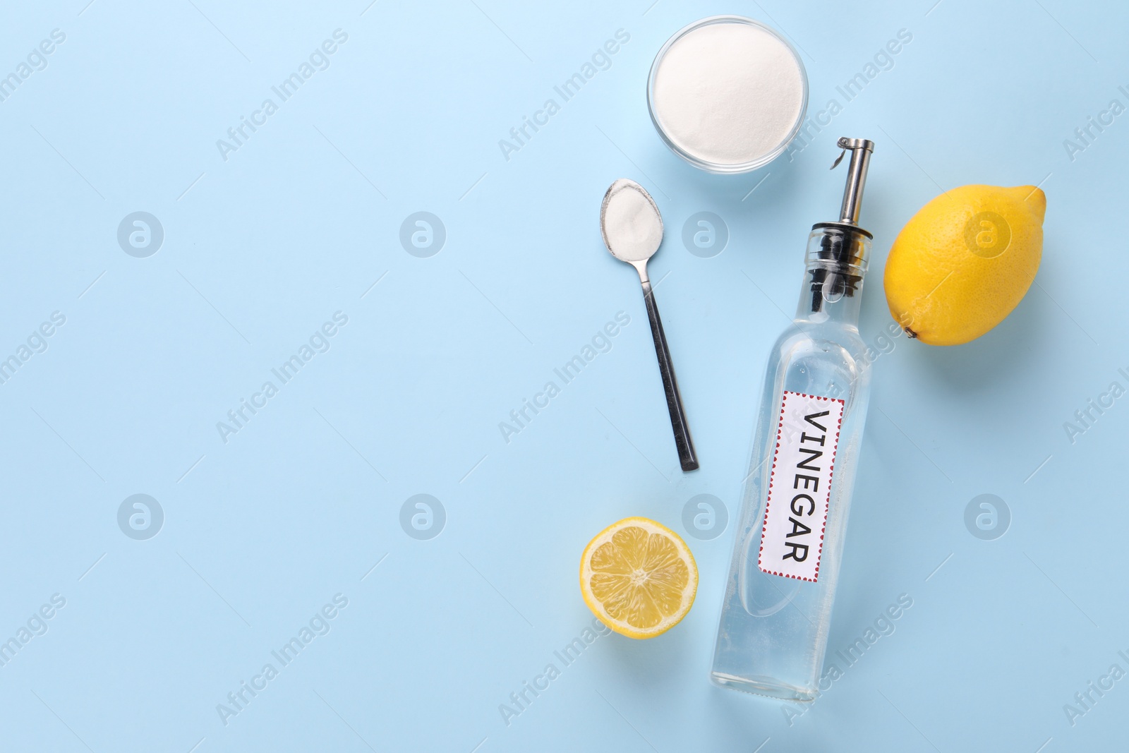 Photo of Eco friendly natural cleaners. Vinegar in bottle, soda and lemons on light blue background, flat lay. Space for text