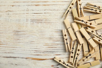 Photo of Pile of clothes pins on white wooden table, flat lay. Space for text