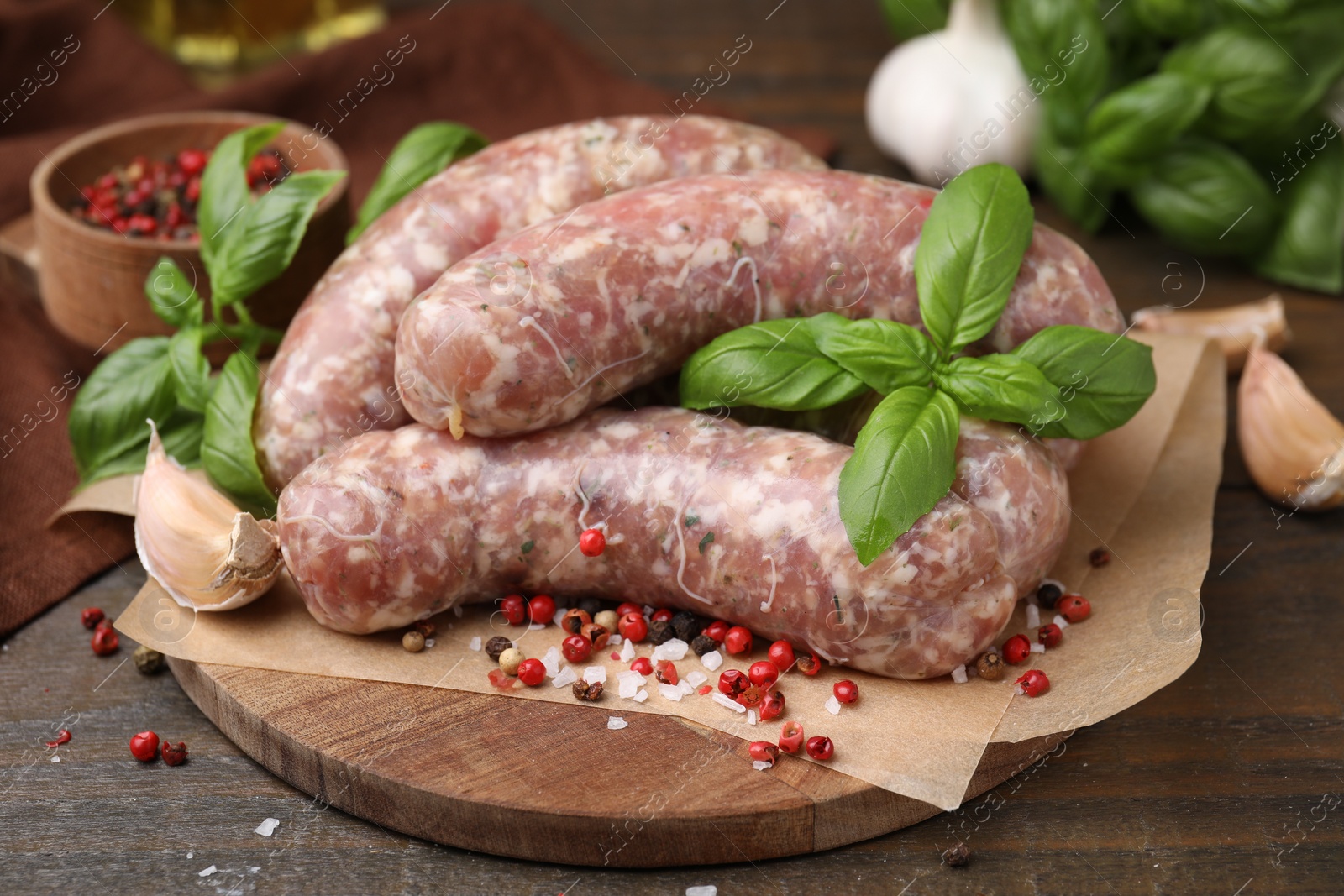 Photo of Raw homemade sausages and different spices on wooden table