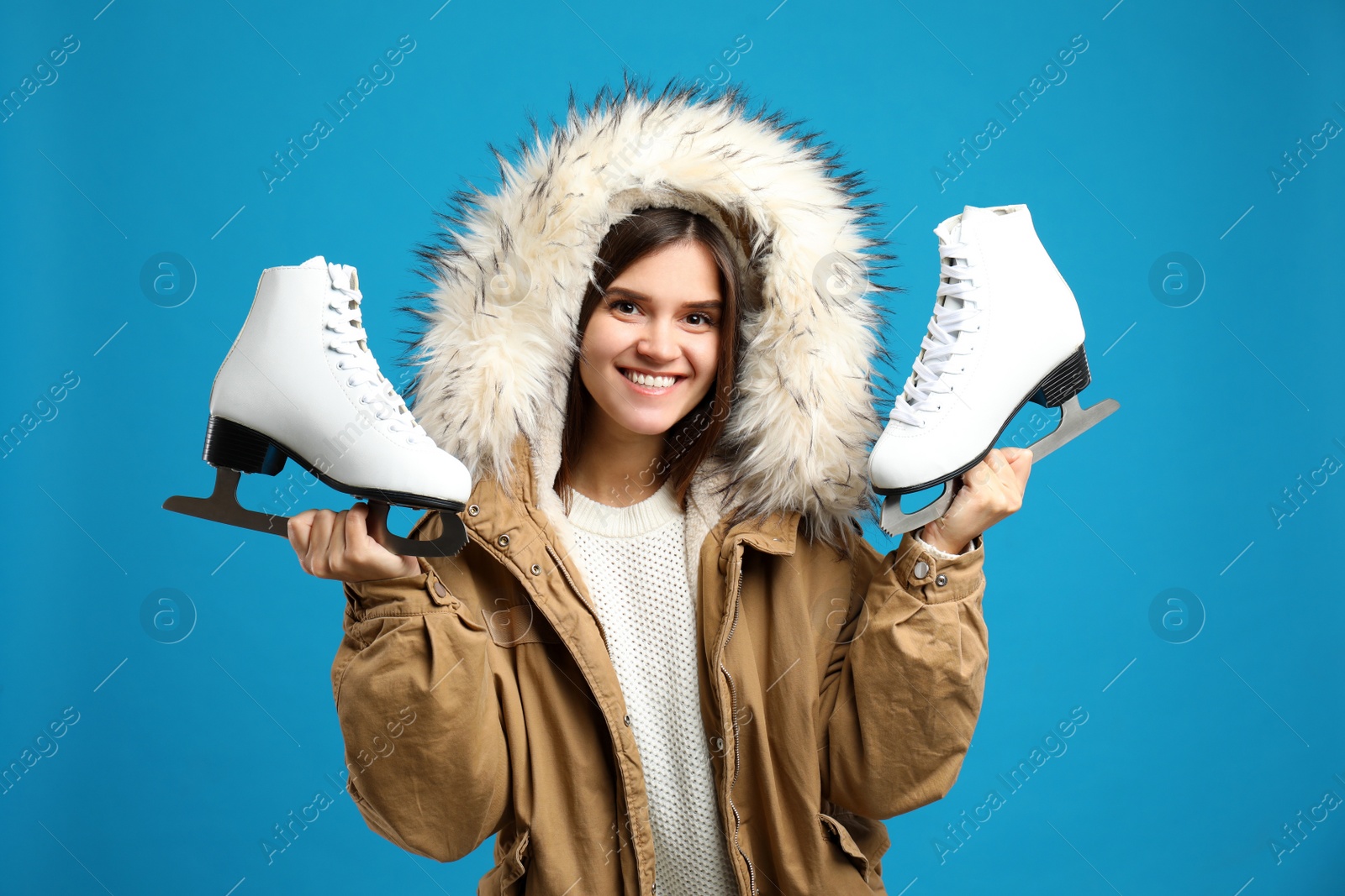 Photo of Happy woman with ice skates on light blue background