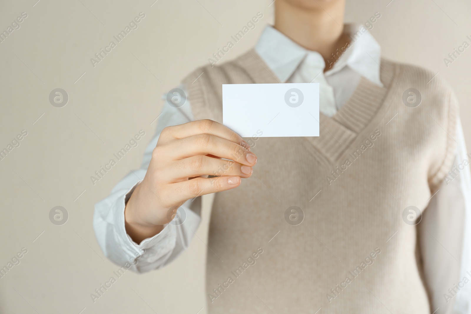 Photo of Woman holding white business card on beige background, closeup