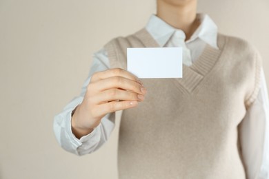 Photo of Woman holding white business card on beige background, closeup