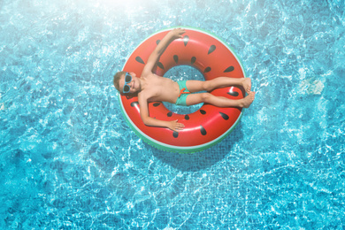 Cute little boy with inflatable ring in swimming pool, top view. Summer vacation