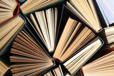 Photo of Many different hardcover books on dark background, top view