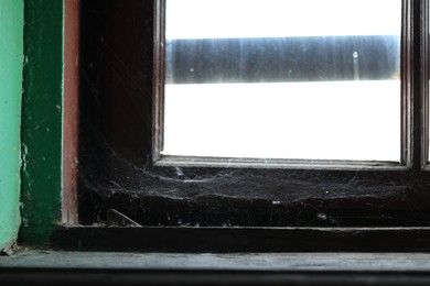 Cobweb on old wooden window frame indoors, closeup