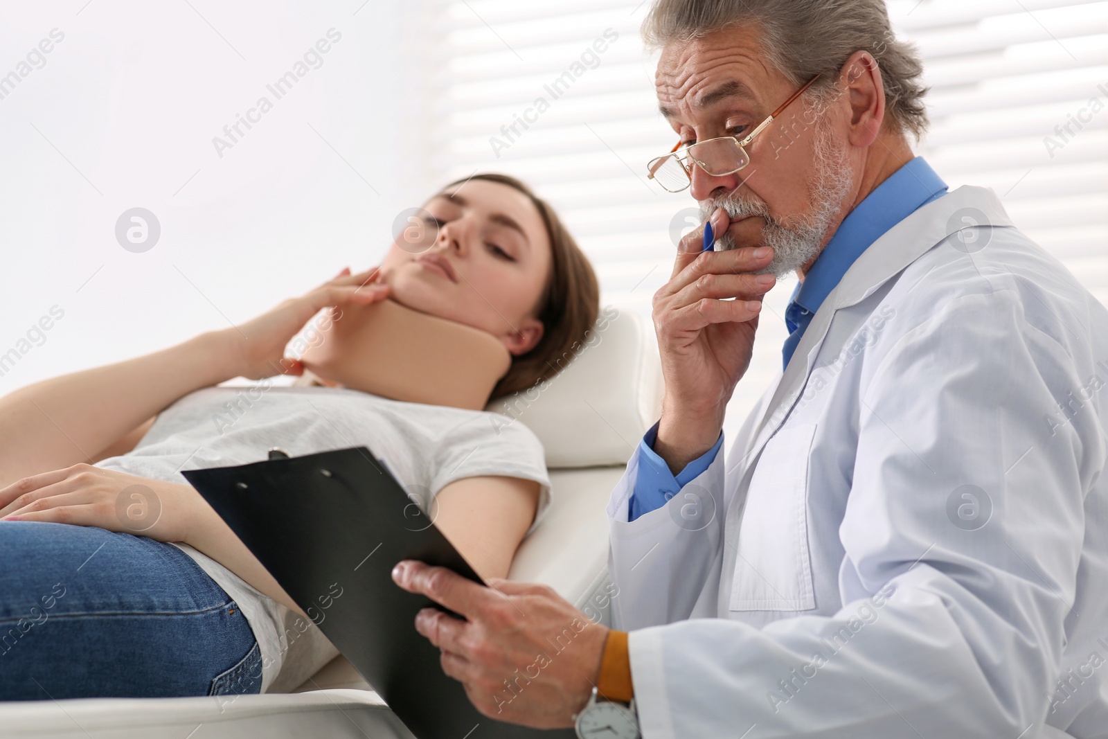 Photo of Orthopedist examining patient with injured neck in clinic