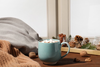 Photo of Cup of cocoa on windowsill indoors, space for text. Winter drink