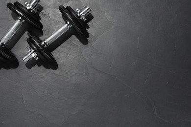 Photo of Barbells on dark textured floor, top view. Space for text