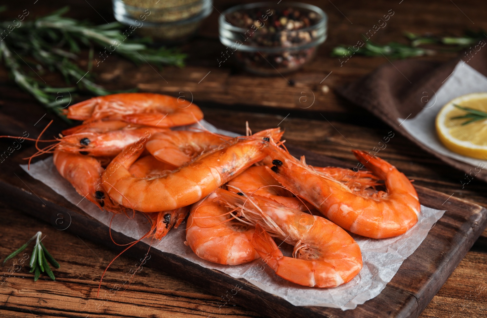 Photo of Delicious cooked shrimps and rosemary on wooden table