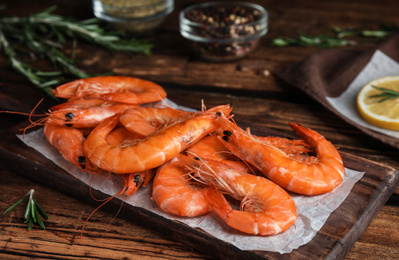 Photo of Delicious cooked shrimps and rosemary on wooden table