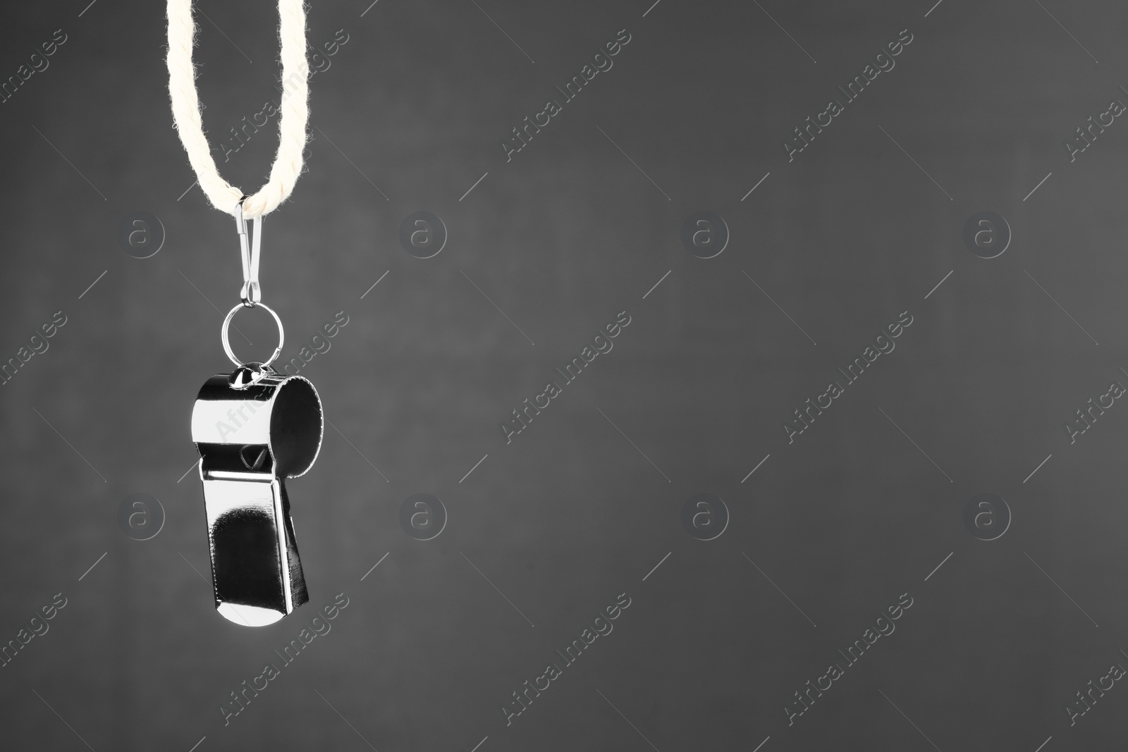 Photo of Referee whistle against black chalkboard, closeup. Space for text