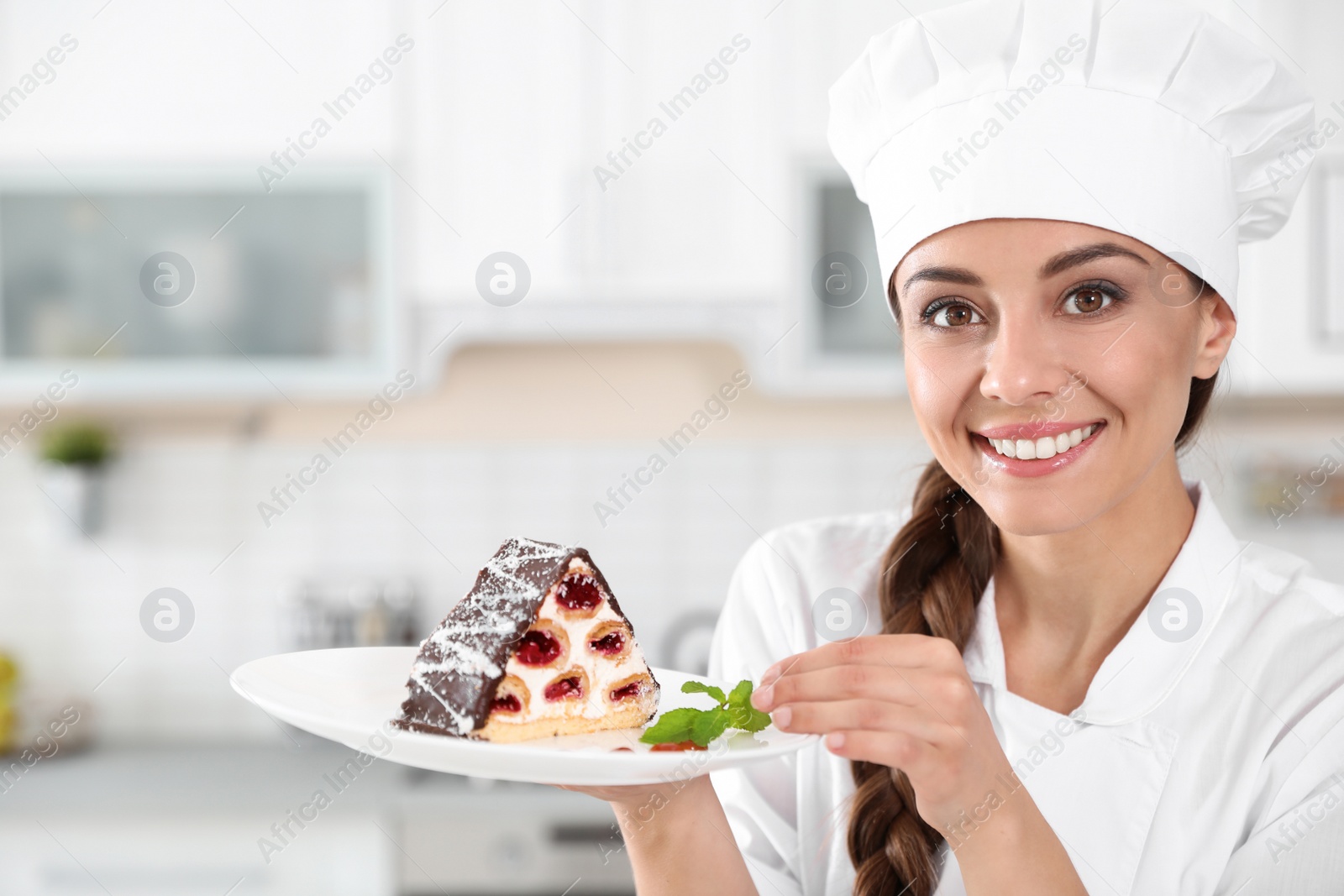 Photo of Professional female chef with plate of delicious dessert in kitchen
