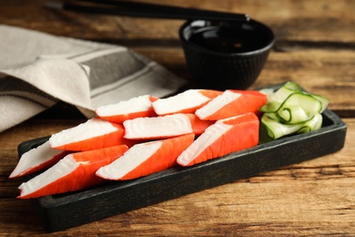 Fresh crab sticks with cucumber served on wooden table, closeup