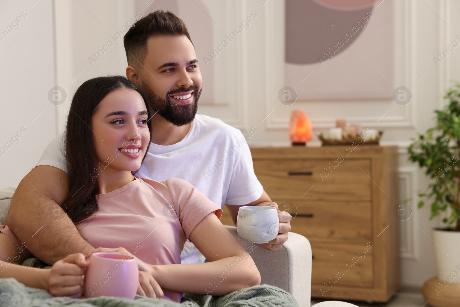 Photo of Happy young couple spending time together in living room. Space for text