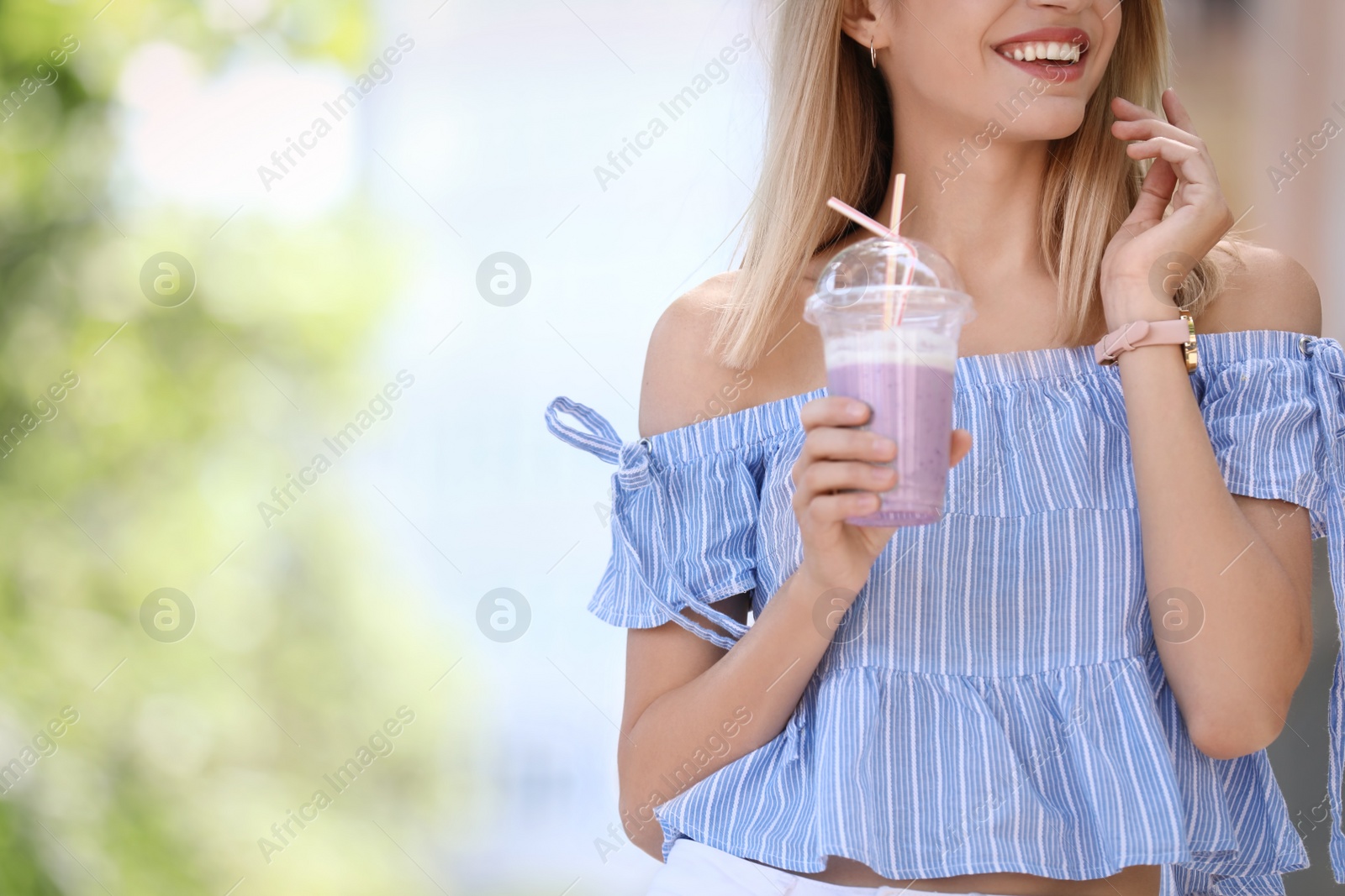 Photo of Young woman with plastic cup of healthy smoothie outdoors