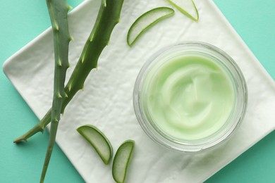 Jar of natural cream and aloe leaves on green background, top view