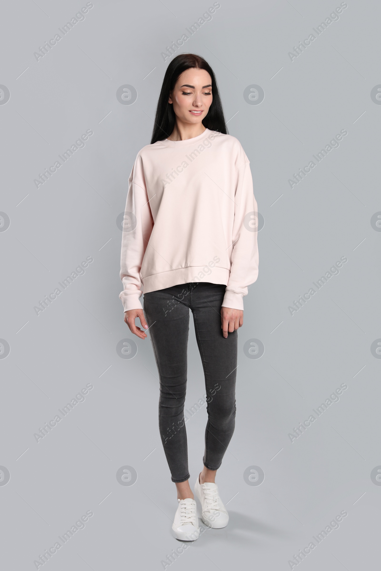 Photo of Full length portrait of young woman in sweater on grey background. Mock up for design