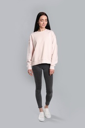 Photo of Full length portrait of young woman in sweater on grey background. Mock up for design