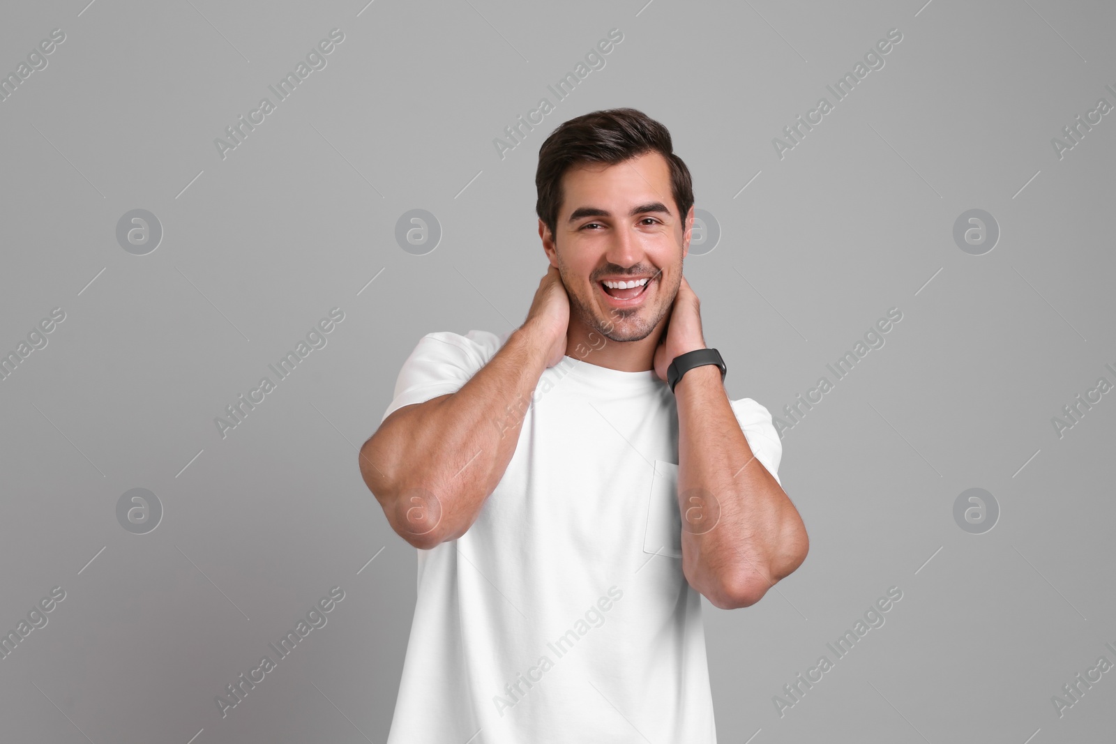 Photo of Portrait of handsome young man in white t-shirt on grey background