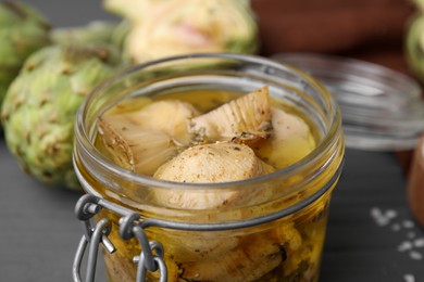 Jar of delicious artichokes pickled in olive oil on table, closeup