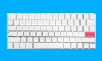 Image of Keyboard with text KEYWORDS on blue background, top view