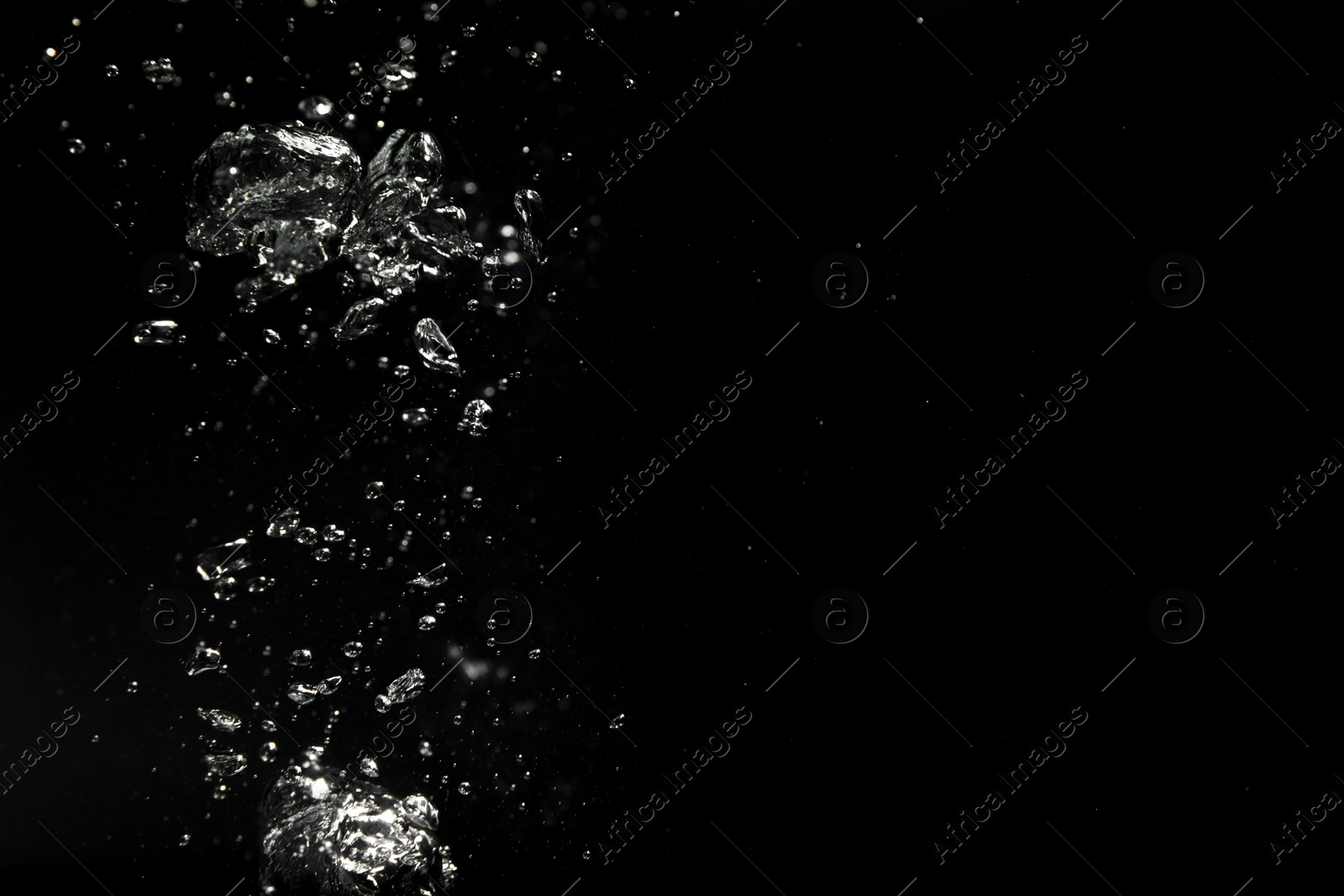 Photo of Air bubbles in water on black background, space for text