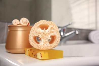 Photo of Loofah sponge and cosmetic products on sink in bathroom