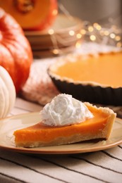 Photo of Piece of fresh homemade pumpkin pie with whipped cream on table