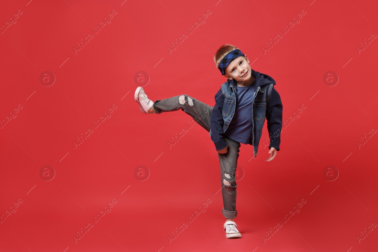 Photo of Happy little boy dancing on red background