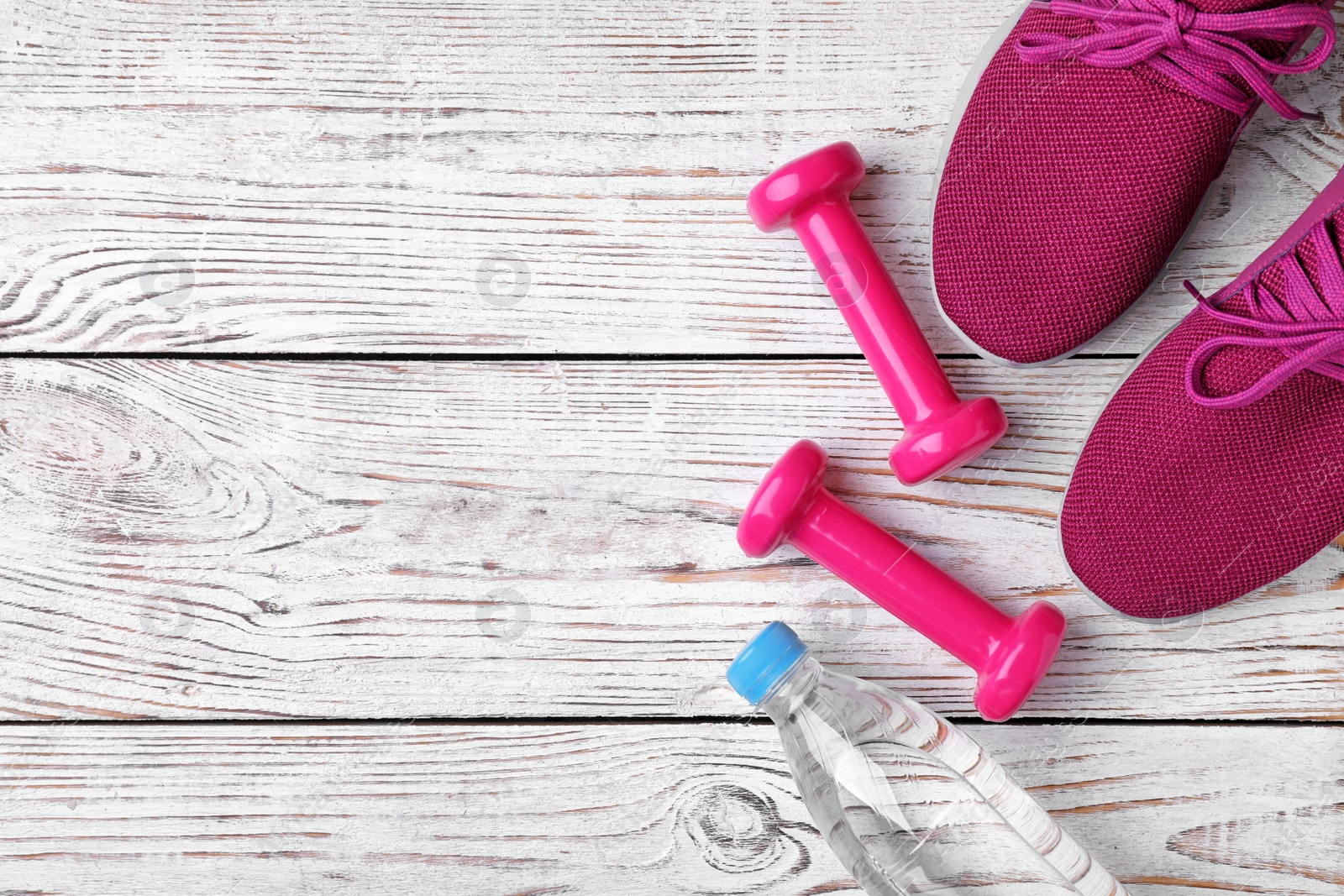 Photo of Flat lay composition with dumbbells, sneakers and space for text on wooden background