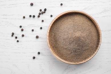 Photo of Ground black pepper and corns on white wooden table, flat lay