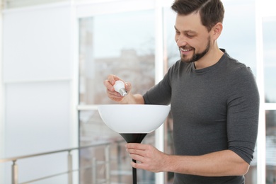 Photo of Man changing light bulb in lamp indoors. Space for text