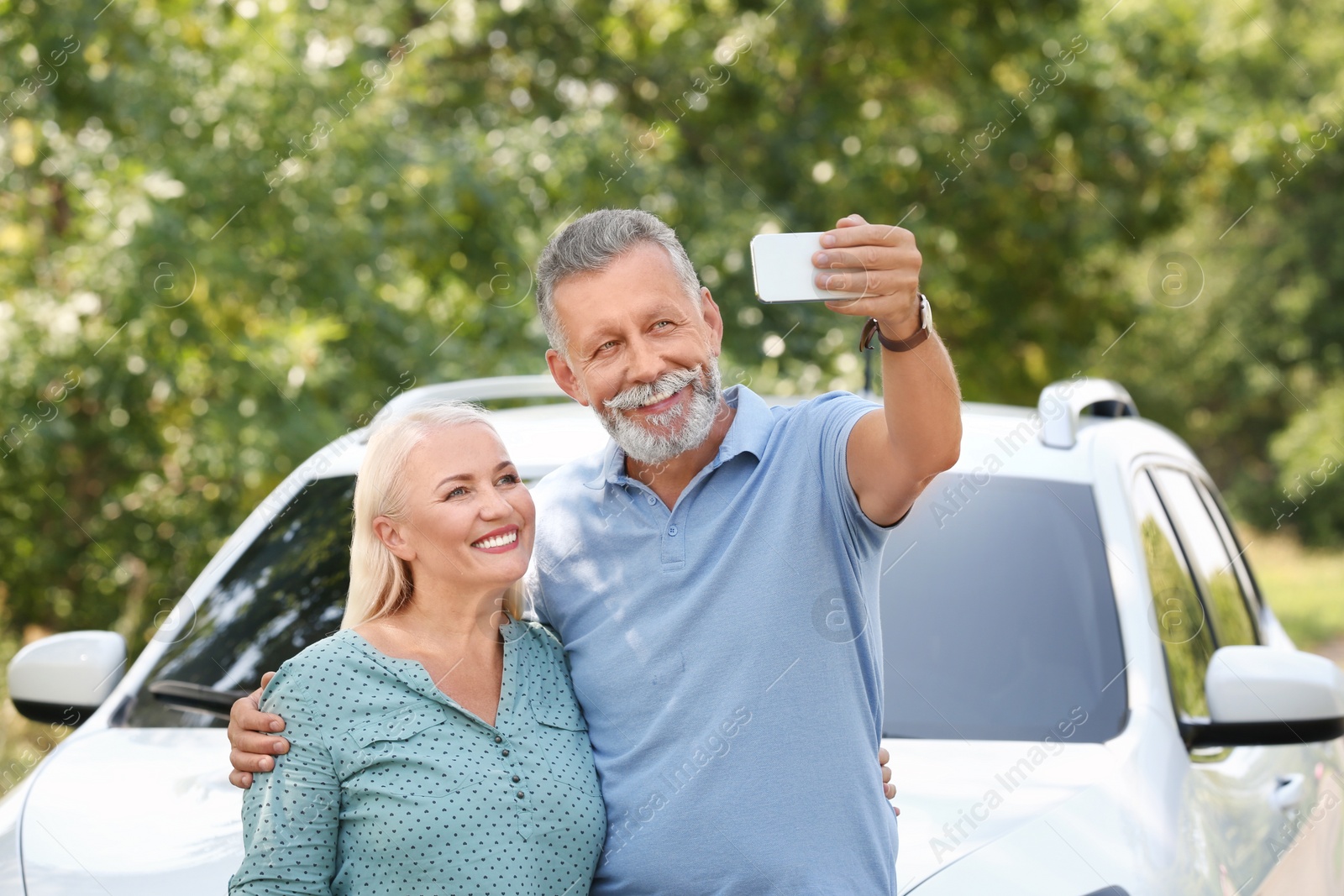 Photo of Happy senior couple taking selfie near car outdoors