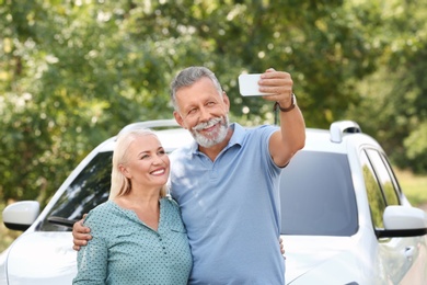 Photo of Happy senior couple taking selfie near car outdoors