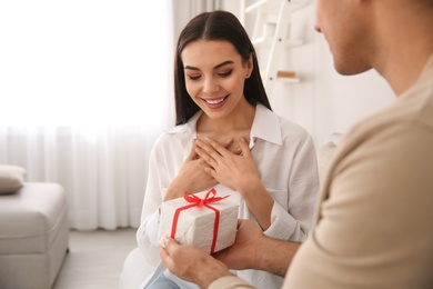 Man presenting gift to his beloved woman at home. Valentine's day celebration