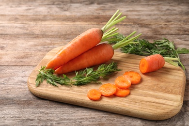 Photo of Board with cut carrot on wooden background