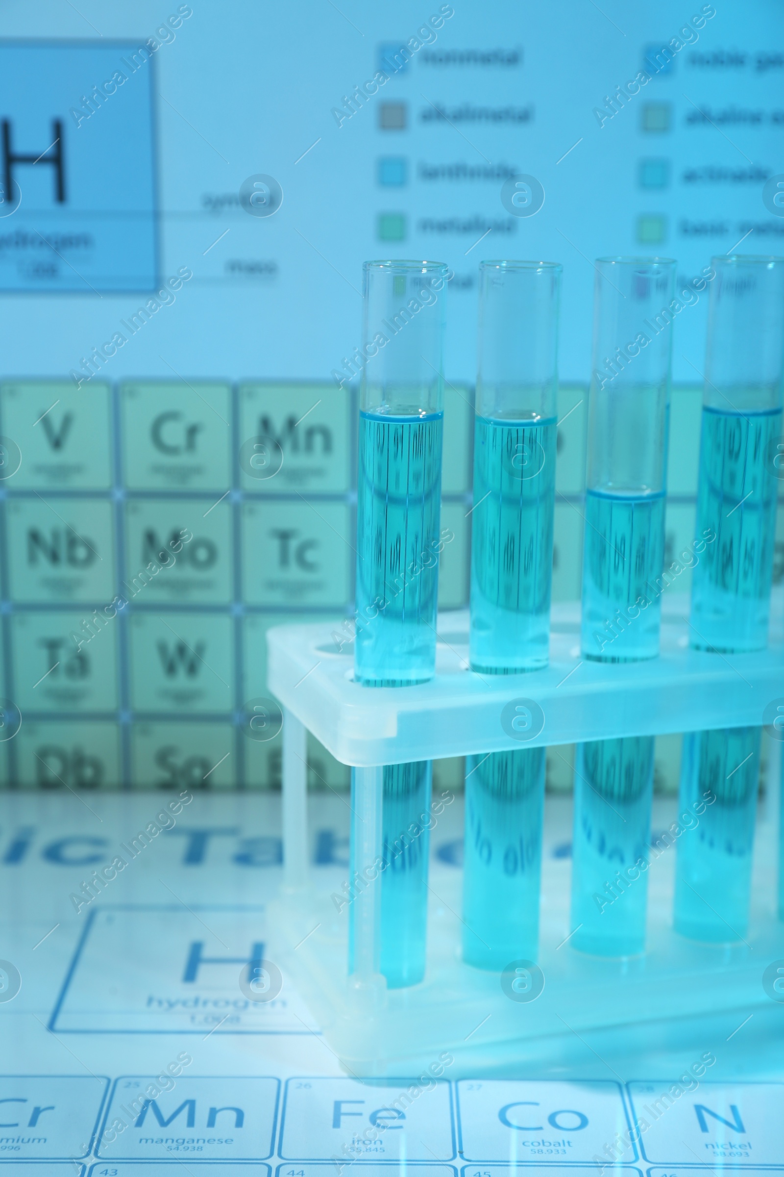 Photo of Test tubes against periodic table of elements, closeup. Color tone effect