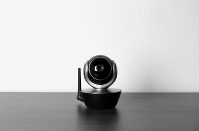 Photo of Baby monitor on wooden table against white background. CCTV equipment