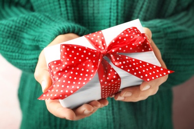 Photo of Woman holding beautiful Christmas gift with bow, closeup