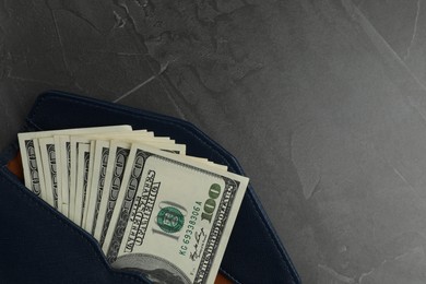 Photo of Money exchange. Wallet with dollar banknotes on dark gray textured background, top view. Space for text