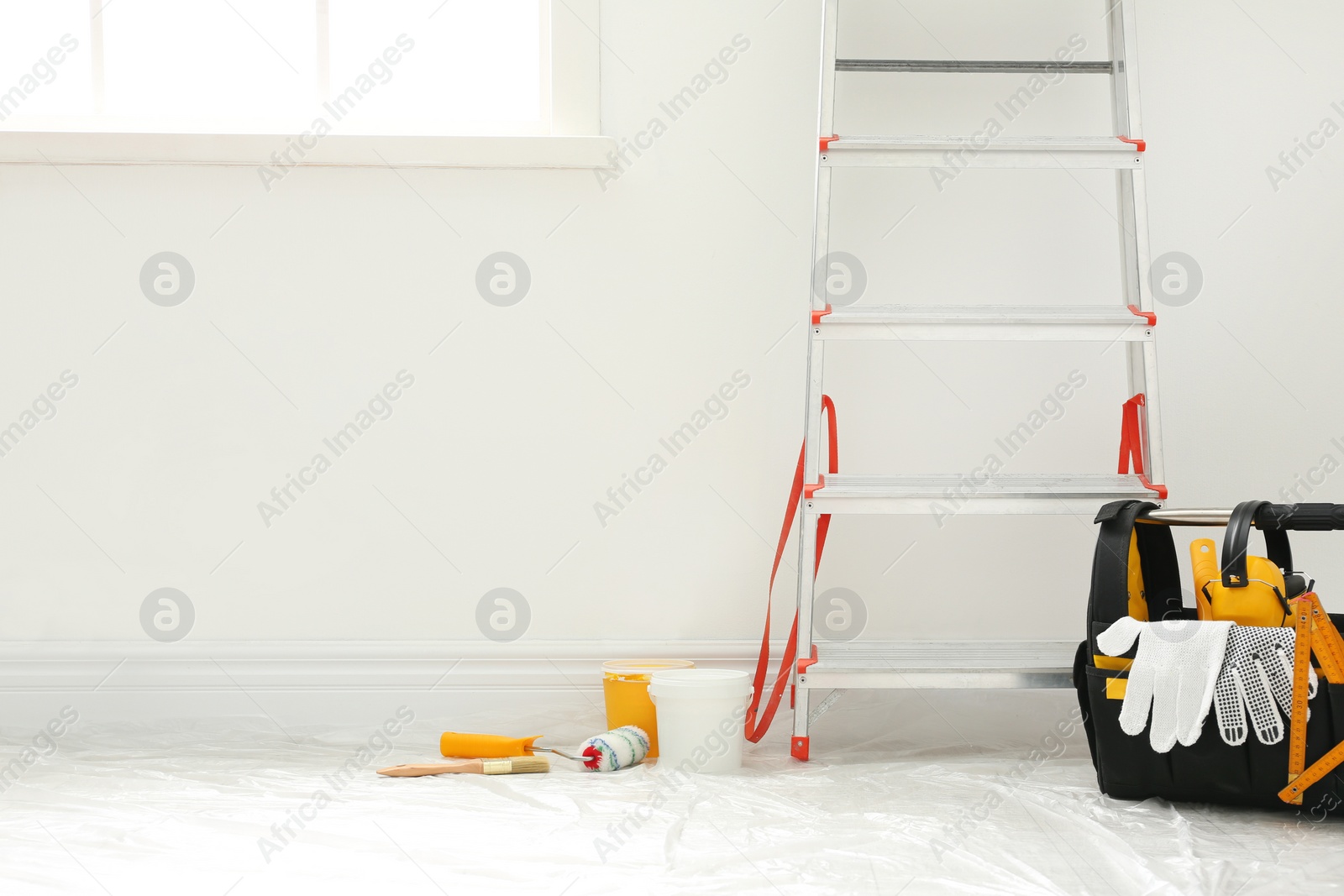 Photo of Stepladder and different tools near wall in room. Interior renovation