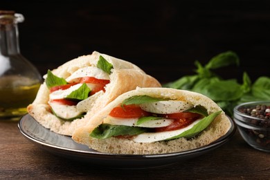 Photo of Delicious pita sandwiches with mozzarella, tomatoes and basil on wooden table, closeup