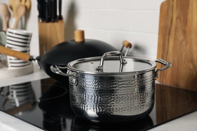 Metal pot and wok on cooktop in kitchen, closeup. Cooking utensils