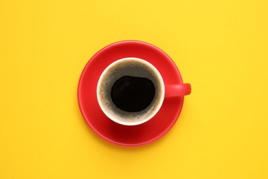 Photo of Aromatic coffee in red cup on yellow background, top view