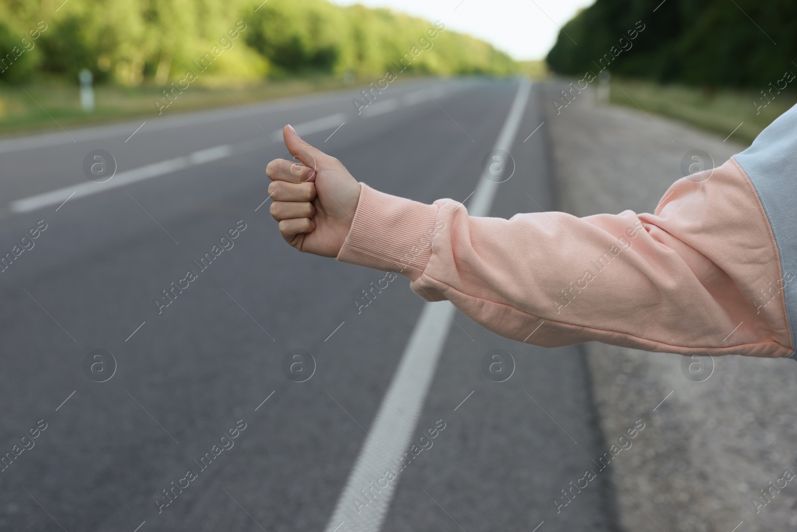 Photo of Woman catching car on road, closeup. Hitchhiking trip