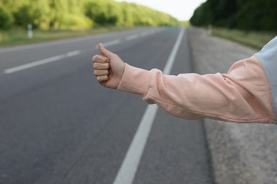 Woman catching car on road, closeup. Hitchhiking trip