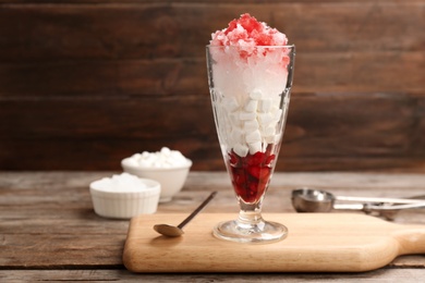 Glass of snow ice cream with raspberry and  marshmallow on table against wooden background. Space for text