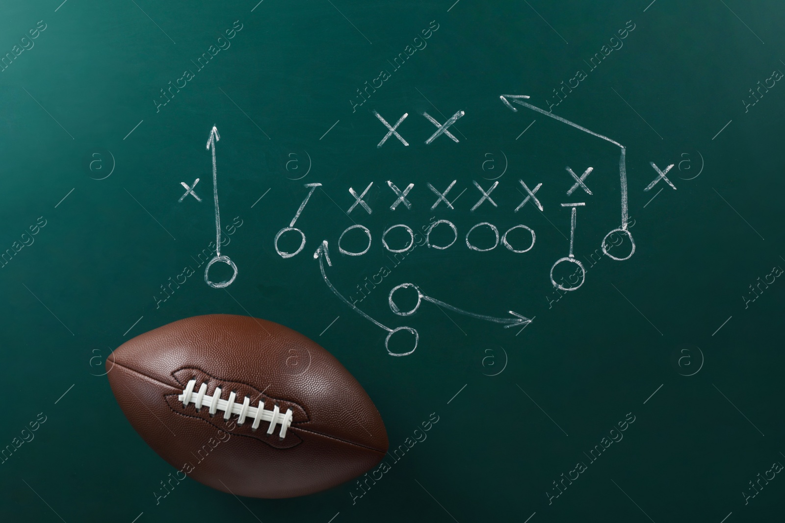 Photo of Leather American football on chalkboard with scheme of game, top view